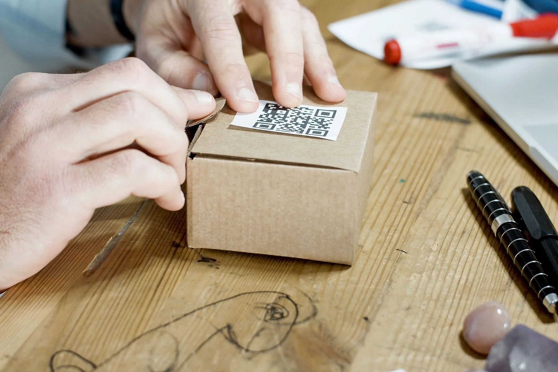 Tay đang dán nhãn mã QR lên hộp hàng — ảnh minh họa Pexels.